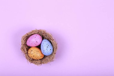 Pembe arka planda üç renkli paskalya yumurtası yuvada