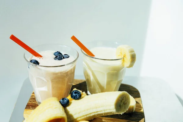两杯香蕉蓝莓奶昔或冰沙 白底上有吸管和香蕉 — 图库照片
