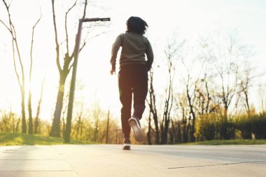 Bulanık görüntü. Parkta gün batımında yolda koşan genç bayan.