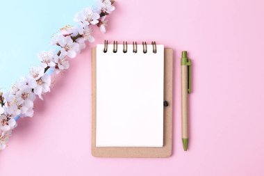 Güzel pembe arka plan, bahar çiçekleri dalları ve defter, üst manzara, düz yatak, çerçeve. Sıfır Atık