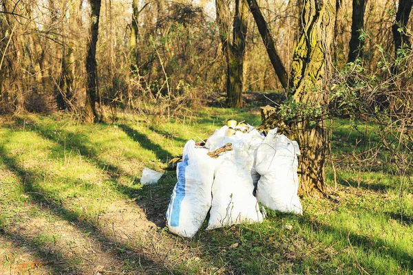 Pile of garbage in bags on green grass in the nature. Environment problems. Pollution