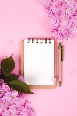Pembe arka planda sakura çiçekleri olan boş bir defter. Sıfır atık