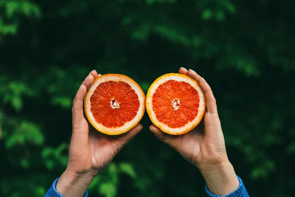 Hands holding a red grapefruit. Healthy lifestyle and food concept. Nature background