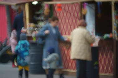 Arka plan bulanık. Çocuklu bir aile eğlence parkında yürüyor..