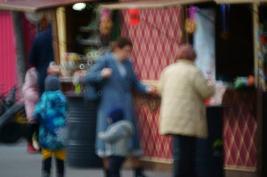 Arka plan bulanık. Çocuklu bir aile eğlence parkında yürüyor..