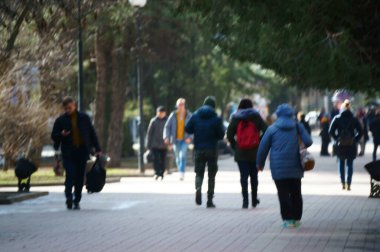 Arka plan bulanık. İnsanlar şehrin caddesi boyunca yürür. Şehir hayatı. Kalabalığın hareketi. İnsan siluetleri. Aile tatili.