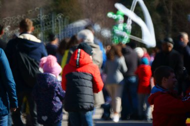 Arka plan bulanık. İnsanlar eğlence parkında yürüyor..