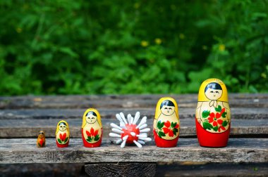 Bir sıra tahta oyuncak bebek. Aralarında bir virüsün plastik figürü var..