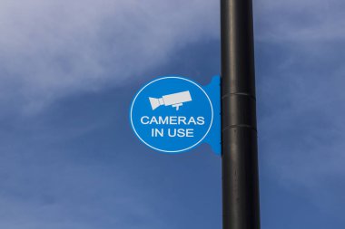 Mavi güvenlik kamera kullanım işareti siyah yazı ve kısmen güneşli arka plan III