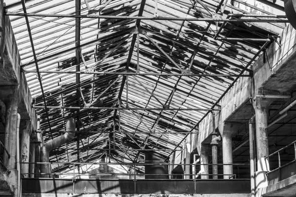 Interior of an abandoned factory in black and white. Broken glass and crumbling cement mark a once busy factory I