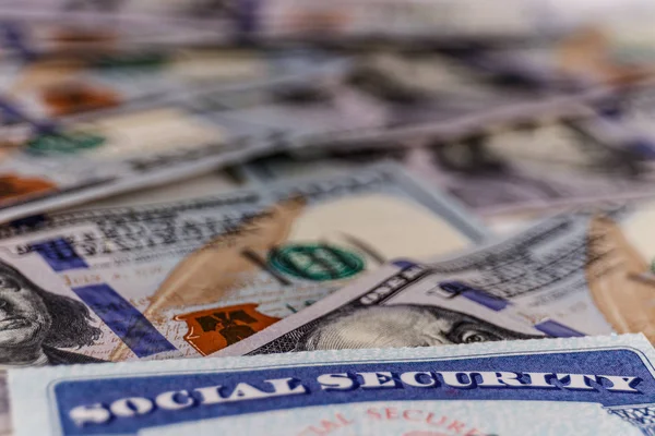 Social Security-kort och en bädd av pengar som representerar de höga kostnaderna för lever på en fast inkomst jag — Stockfoto