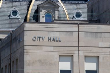 City Hall in silver text set against limestone bricks. clipart