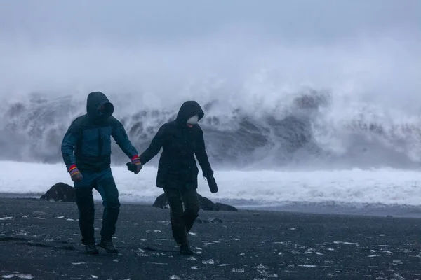 Una pareja amorosa está caminando a lo largo de la orilla de un océano furioso . — Foto de Stock