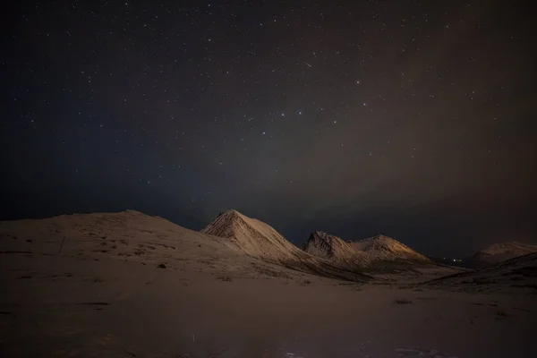 Dramatisk natt med många moln och stjärnor på himlen över bergen i norra Europa - Tromso, Norge.Long slutartid. — Stockfoto