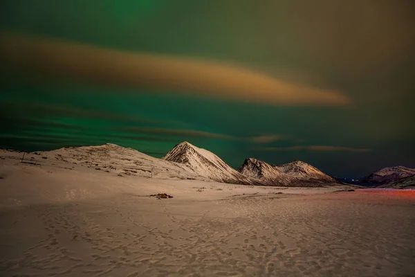 Dramatiska polarljus, Aurora borealis med många moln och stjärnor på himlen över bergen i norra Europa - Tromso, Norge.Long slutartid. — Stockfoto