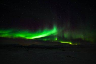 Dramatik kutup ışıkları, Kuzey Avrupa 'daki dağların üzerinden gökyüzünde birçok bulut ve yıldız bulunan Aurora borealis Abisko, İsveç. uzun deklanşör hızı.