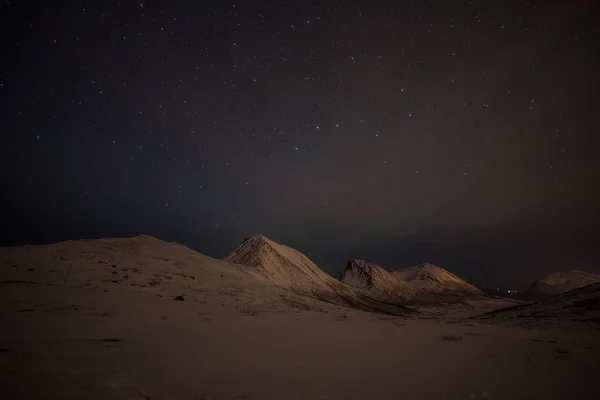 Noche dramática con muchas nubes y estrellas en el cielo sobre las montañas en el norte de Europa - Tromso, Noruega.larga velocidad de obturación . — Foto de Stock