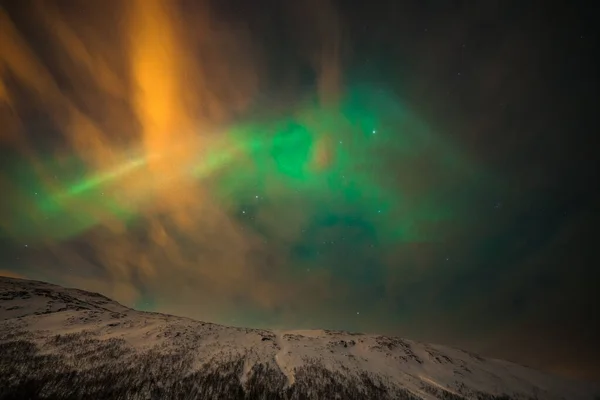Luzes polares dramáticas, Aurora boreal com muitas nuvens e estrelas no céu sobre as montanhas no norte da Europa - Tromso, Norway.long velocidade do obturador . — Fotografia de Stock