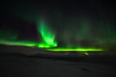 Dramatik kutup ışıkları, Kuzey Avrupa 'daki dağların üzerinden gökyüzünde birçok bulut ve yıldız bulunan Aurora borealis Abisko, İsveç. uzun deklanşör hızı.