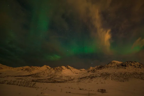 Luces polares dramáticas, Aurora boreal con muchas nubes y estrellas en el cielo sobre las montañas en el norte de Europa - Tromso, Noruega.Larga velocidad de obturación . — Foto de Stock