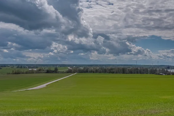 Cielo tormentoso sobre un campo verde sembrado con energía eólica en el fondo. Centro de Suecia . — Foto de Stock