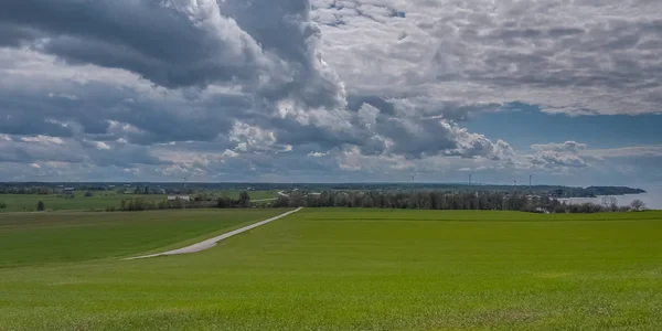 Cielo tormentoso sobre un campo verde sembrado con energía eólica en el fondo. Centro de Suecia . — Foto de Stock