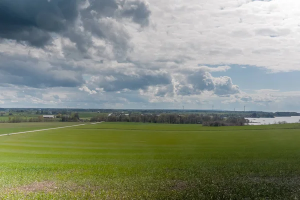 Cielo tormentoso sobre un campo verde sembrado con energía eólica en el fondo. Centro de Suecia . —  Fotos de Stock