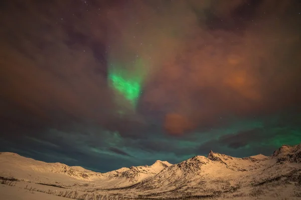 Dramatiska polarljus, Aurora borealis med många moln och stjärnor på himlen över bergen i norra Europa - Tromso, Norge.Long slutartid. — Stockfoto