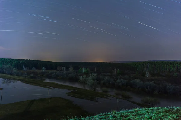 Huellas de estrellas se reflejan en el río durante una inundación. Rusia. larga velocidad de obturación. enfoque selectivo — Foto de Stock