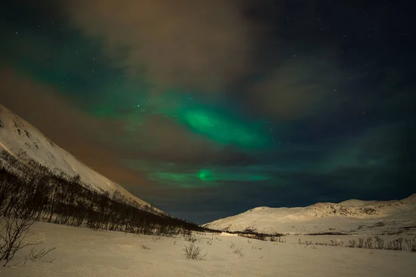 Luzes polares dramáticas, Aurora boreal com muitas nuvens e estrelas no céu sobre as montanhas no norte da Europa - Tromso, Norway.long velocidade do obturador . — Fotografia de Stock