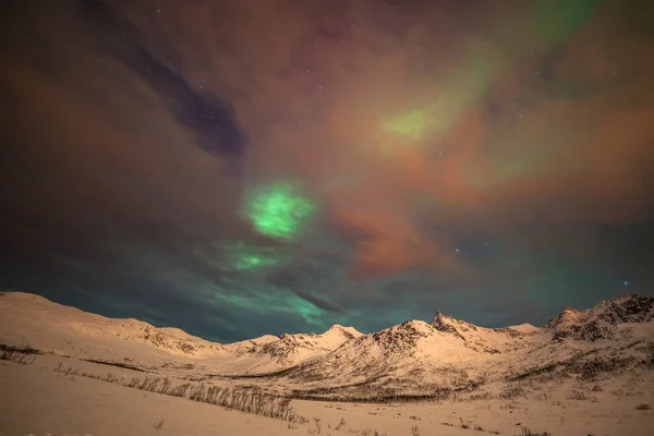 Luzes polares dramáticas, Aurora boreal com muitas nuvens e estrelas no céu sobre as montanhas no norte da Europa - Tromso, Norway.long velocidade do obturador . — Fotografia de Stock