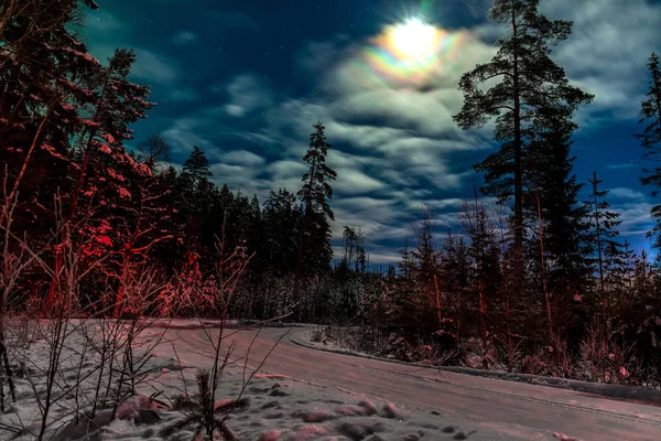 Moon shines the snowy road in a forest in Sweden. red light from a leaving car — 스톡 사진