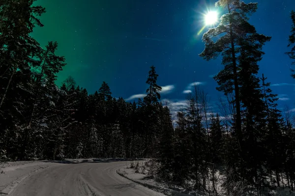 Lua brilha a estrada nevada em uma floresta na Suécia — Fotografia de Stock