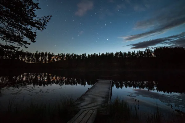 Un millón de estrellas en el cielo nublado sobre el lago en la noche. puente en primer plano. larga exposición. Vía Láctea — Foto de Stock