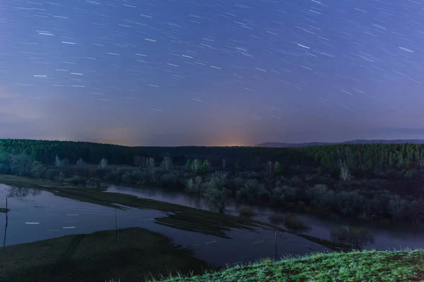 Huellas de estrellas se reflejan en el río durante una inundación. Rusia. larga velocidad de obturación. enfoque selectivo — Foto de Stock