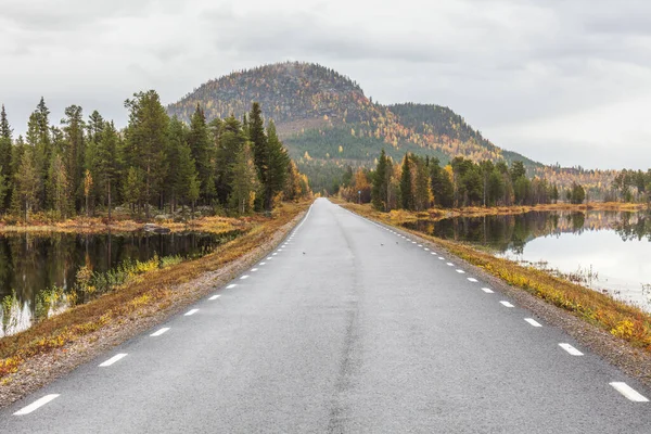 Gün batımında göl boyunca uzanan yol dağlara çıkar.. — Stok fotoğraf