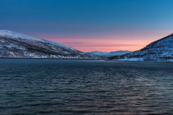Increíble puesta de sol con increíble color magenta sobre fiordo Tromso, Noruega. Noche polar. larga velocidad de obturación — Foto de Stock