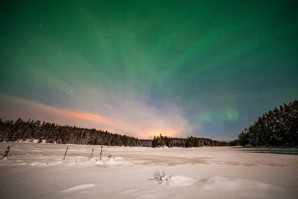 Dramatic polar lights, Aurora borealis with many clouds and stars by moonlight on the sky over a frozen lake and snowy forest in Sweden. long shutter speed.