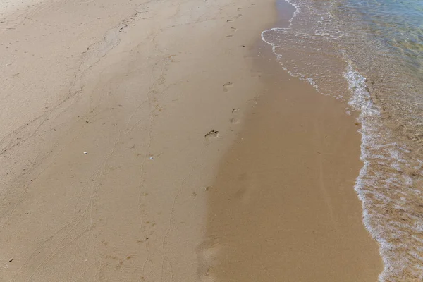 人类在大海里沙滩上的脚印。 沙质。 褐色沙子的背景. — 图库照片