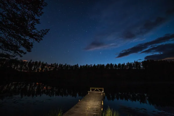 Un millón de estrellas sobre el lago por la noche. puente en primer plano. larga exposición. Vía Láctea — Foto de Stock
