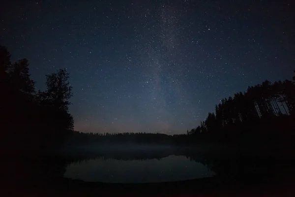 Un million d'étoiles au-dessus du lac la nuit. longue exposition. Sentier depuis un satellite volant. Voie lactée — Photo