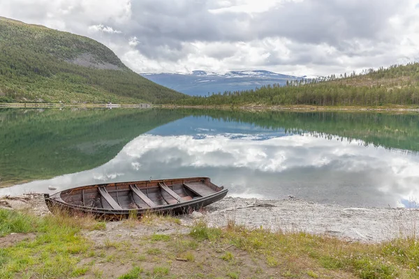 Paisaje noruego con un barco en el lago contra montañas. Barco de pesca en un lago tranquilo en Noruega y altas montañas en el fondo. Barco de pesca — Foto de Stock
