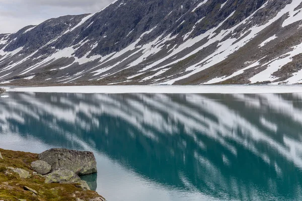 Snow mountains surrounded by clouds in norwegian fiord reflection in water, selective focus — 스톡 사진