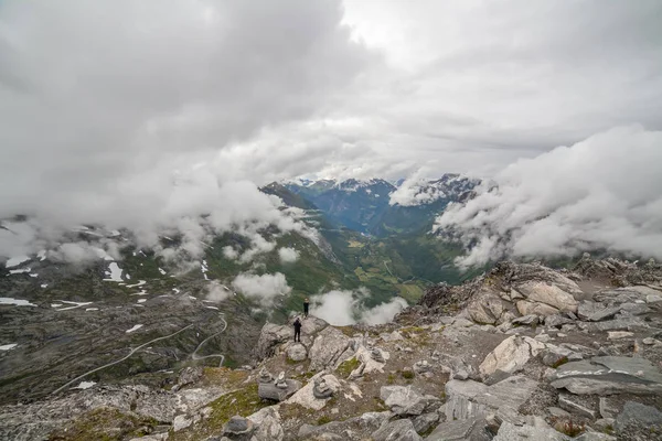 Pareja enamorada parada en el borde de la montaña Vista a Geiranger fiordo y camino de águila en tiempo nublado de la montaña Dalsnibba, carretera serpentina, Noruega, enfoque selectivo . — Foto de Stock