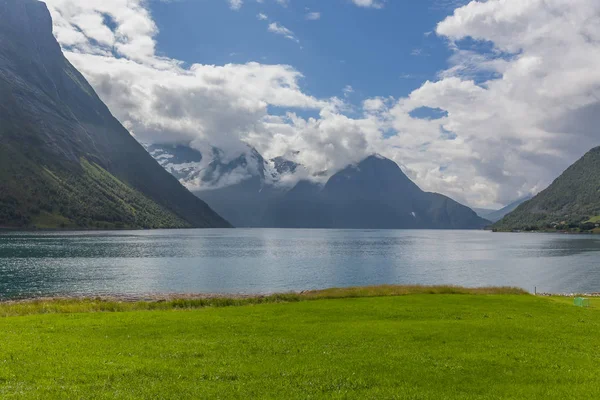 Un fiordo místico en Noruega con montañas y niebla colgando sobre el agua en un hermoso color azul monocromo. enfoque selectivo — Foto de Stock