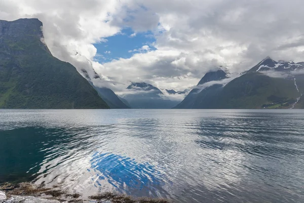 Fiordo noruego y montañas rodeadas de nubes, reflejo ideal de fiordo en aguas cristalinas. enfoque selectivo . — Foto de Stock