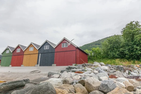 Gaviota enojada está volando por encima de las casas de botes. casas de madera garaje multicolor en pueblo pesquero noruego costero . — Foto de Stock