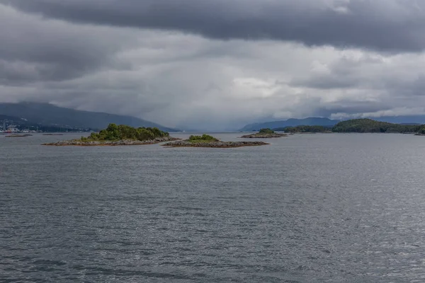 Ένα μυστικιστικό φιόρδ στη Νορβηγία με βουνά και ομίχλη να κρέμονται πάνω από το νερό σε ένα όμορφο μονόχρωμο μπλε χρώμα. — Φωτογραφία Αρχείου