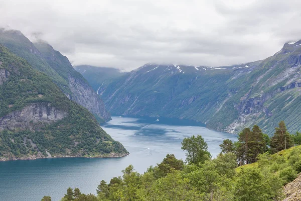 Mystický fjord v Norsku s horami a mlhou visící nad vodou v krásné monochromatické modré barvě. — Stock fotografie