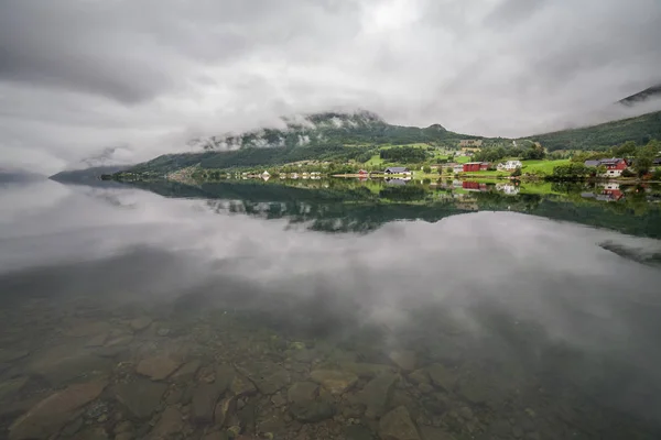 Ένα μυστικιστικό φιόρδ στη Νορβηγία με βουνά και ομίχλη να κρέμονται πάνω από το νερό σε ένα όμορφο μονόχρωμο μπλε χρώμα. — Φωτογραφία Αρχείου